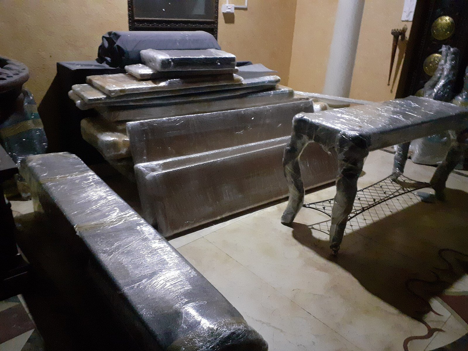Household furniture including a table, benches and stacked items wrapped in clear cling film plastic wrap in preparation for a house move